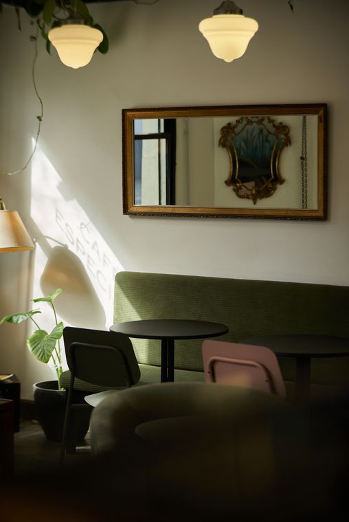 Mesas y sillones verdes bajo un espejo antiguo